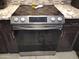 Stainless steel oven and electric stovetop with granite countertops and dark brown cabinets at 10407 W Reade Ave, Glendale, AZ 85307