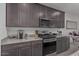 Modern kitchen with stainless steel appliances, granite countertops, and stylish dark cabinets at 10986 W Polk St, Avondale, AZ 85323