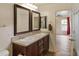 Bathroom features a double sink vanity with granite countertops, decorative framed mirrors and wood-look flooring at 11454 W St John Rd, Surprise, AZ 85378