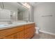 Bathroom featuring wood cabinets, double sinks, large mirror, light gray walls, and shower with glass door at 11640 N Tatum Blvd # 1031, Phoenix, AZ 85028