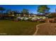 Multi-tiered stone waterfall with lush landscaping and a grassy lawn at dusk at 12335 W Rosewood Ln, Peoria, AZ 85383