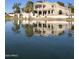 Waterfront home with two-story architecture, balcony, lush palms, and a calm lake view at 1414 N Palmsprings Dr, Gilbert, AZ 85234