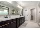 Double vanity bathroom featuring espresso cabinets with matte gold hardware, tile floors, and a framed mirror at 17652 W Straight Arrow Ln, Surprise, AZ 85387