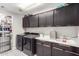 Well-organized laundry room featuring shaker cabinets, modern washer and dryer, and patterned tile floor at 17652 W Straight Arrow Ln, Surprise, AZ 85387