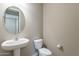 Stylish powder room with pedestal sink, large mirror, and designer lighting fixtures at 18766 W Montebello Ave, Litchfield Park, AZ 85340