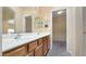 Bathroom featuring double sinks, wood cabinetry and a view of the walk-in closet at 1909 N 106Th Ave, Avondale, AZ 85392