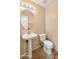 Cozy half bathroom featuring a pedestal sink, oval mirror and neutral color palette at 1909 N 106Th Ave, Avondale, AZ 85392
