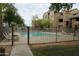 View of a fenced community pool area surrounded by grassy areas and a multi-story condo building at 200 E Southern Ave # 133, Tempe, AZ 85282