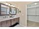 Bathroom featuring double sink vanity with dark wood cabinets and a walk-in closet at 2418 W White Feather Ln, Phoenix, AZ 85085