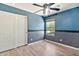 Inviting bedroom with blue and gray accent wall, ceiling fan, and wood-look floors at 2418 W White Feather Ln, Phoenix, AZ 85085