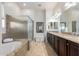 A primary bathroom features granite counters, tile floor, bath tub and glass enclosed shower at 26065 N 74Th Dr, Peoria, AZ 85383