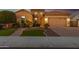 Beautiful home with a well-manicured front yard, illuminated entrance, and a two-car garage and stone accents at 26065 N 74Th Dr, Peoria, AZ 85383
