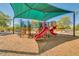 Colorful playground equipment shaded by a green canopy, set on a wood chip surface at 26065 N 74Th Dr, Peoria, AZ 85383