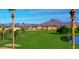 A picturesque golf course view with palm trees, a lake, and mountains in the distance under a clear blue sky at 2635 N 62Nd St, Mesa, AZ 85215
