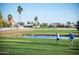Scenic golf course view with a pond, lush green grass, and palm trees, under a blue sky at 2635 N 62Nd St, Mesa, AZ 85215