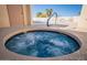 Inviting hot tub with swirling blue water, surrounded by a tiled border and a community pool area at 2635 N 62Nd St, Mesa, AZ 85215