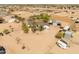 Aerial view of a ranch-style home, sheds, and horse facilities in a sprawling desert landscape at 28061 N Holly Rd, San Tan Valley, AZ 85143