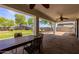 Spacious covered patio with a dark-wood dining table looking out onto a large grassy backyard with mature shade trees at 28061 N Holly Rd, San Tan Valley, AZ 85143