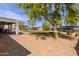 Picturesque backyard featuring a covered patio, lush green lawn, mature trees, and a gravel area for versatile outdoor living at 28061 N Holly Rd, San Tan Valley, AZ 85143