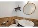 Stylish powder room featuring a round mirror, custom shelving, and a pedestal sink with decorative tile backsplash at 4411 N 24Th Way, Phoenix, AZ 85016