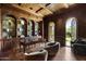 Richly appointed office features custom shelving, elegant furniture, and an arched doorway leading to the outdoors at 6852 E Fanfol Dr, Paradise Valley, AZ 85253