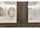 Bright bathroom featuring dual sinks, oval mirrors, white countertops, and a central storage cabinet at 7326 W Pershing Ave, Peoria, AZ 85381
