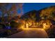 A grand, illuminated entrance gate with brick driveway leading to a luxury home at night at 7801 N Saguaro Dr, Paradise Valley, AZ 85253