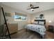 Cozy bedroom with wood flooring, ceiling fan, and a window view of swaying palm trees at 8132 E Valley View Rd, Scottsdale, AZ 85250