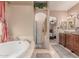 Luxurious bathroom with a soaking tub, walk-in shower, and dual sinks with wood cabinets at 9137 E Odessa St, Mesa, AZ 85207