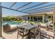 Relaxing backyard with a shimmering pool, outdoor dining area, and stylish lounge seating under a modern pergola at 11705 W Luxton Ln, Avondale, AZ 85323