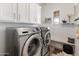 A modern laundry room with front-loading washer and dryer, plus ample storage at 11705 W Luxton Ln, Avondale, AZ 85323