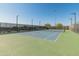 Well-lit tennis court with a green and blue surface, surrounded by a fence and desert landscape at 11705 W Luxton Ln, Avondale, AZ 85323