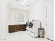 Spacious laundry room with a sink, wood cabinets and large front load washer and dryer at 4571 S Pinaleno W Dr, Chandler, AZ 85249