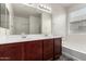 Bathroom featuring a double vanity, soaking tub and warm wood cabinetry at 5750 S 250Th Dr, Buckeye, AZ 85326