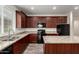 Modern kitchen featuring granite countertops, wood cabinetry, an island and black appliances, with tile floors at 5750 S 250Th Dr, Buckeye, AZ 85326