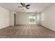 Bright and airy living room featuring neutral carpeting, a ceiling fan, and sliding glass doors at 5750 S 250Th Dr, Buckeye, AZ 85326