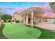 Amazing backyard featuring a putting green, covered patio, and lush landscaping ideal for entertaining and relaxation at 14999 W Mulberry Dr, Goodyear, AZ 85395