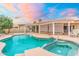 Beautiful pool and spa area featuring a covered patio with seating under a colorful sky, and lush landscaping at 14999 W Mulberry Dr, Goodyear, AZ 85395