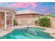 Backyard pool area with a spa, beautiful blue tiles, two white chairs, and a table for poolside relaxation at 14999 W Mulberry Dr, Goodyear, AZ 85395