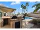 An outdoor kitchen featuring a grill, counterspace and barstools overlooking a pristine swimming pool at 1024 N Ithica Ct, Chandler, AZ 85225