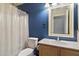 A clean bathroom with blue walls, a white toilet, and a shower with a patterned curtain at 1024 N Ithica Ct, Chandler, AZ 85225