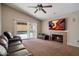 A cozy living room featuring a fireplace, TV, ceiling fan, and sliding doors that lead to a swimming pool at 1024 N Ithica Ct, Chandler, AZ 85225