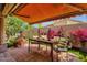 Covered outdoor patio with tiled floor, awning, a wood table set and manicured landscaping at 10591 E Saddlehorn Dr, Scottsdale, AZ 85258