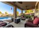 Inviting covered patio with comfortable seating, ceiling fans, and a view of the sparkling pool and landscaped backyard at 1194 E Coyote Creek Way, San Tan Valley, AZ 85143