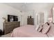Well-lit bedroom showcasing a large TV, dresser, and access to an ensuite bathroom at 18031 W Udall Dr, Surprise, AZ 85374