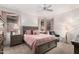 Charming bedroom featuring a ceiling fan, bedside tables, and windows with decorative drapes at 18031 W Udall Dr, Surprise, AZ 85374