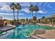 Beautiful community pool featuring palm trees, lush landscaping, and comfortable lounge chairs at 18031 W Udall Dr, Surprise, AZ 85374