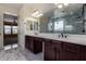 Bright bathroom with double sink vanity, marble floors, a large mirror, and glass walk in shower at 18640 W Pioneer St, Goodyear, AZ 85338