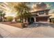 Inviting two-story home with a well-manicured lawn, mature trees, and a two-car garage and warm sunset at 18640 W Pioneer St, Goodyear, AZ 85338