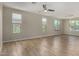 Bright and airy living room with hardwood floors, large windows, and modern ceiling fan at 18640 W Pioneer St, Goodyear, AZ 85338